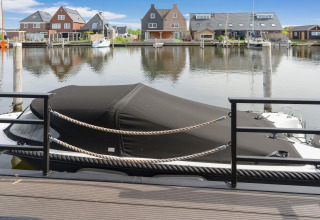 Afgedekte boot aan de steiger voor moderne huizen in Stavoren, Nederland, gezien vanaf een woonboot.