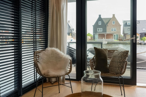 Gezellige zithoek met rieten stoelen en uitzicht op het water, gezien vanuit Boat House Stavoren in Nederland.