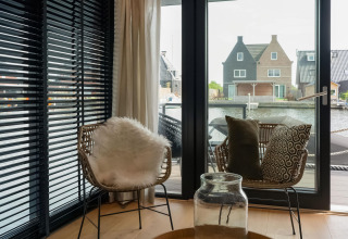 Gezellige zithoek met rieten stoelen en uitzicht op het water, gezien vanuit Boat House Stavoren in Nederland.