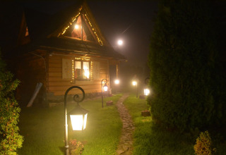 Sfeervol houten chalet in Tsjechië 's nachts verlicht door lantaarns langs een stenen tuinpad.