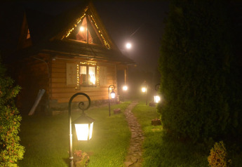 Chalet en bois chaleureux dans les montagnes tchèques, éclairé par des lampadaires sur une allée de nuit.