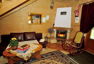 Gezellige woonkamer in een chalet in Tsjechië met open haard, bank, schommelstoel en houten wanden.