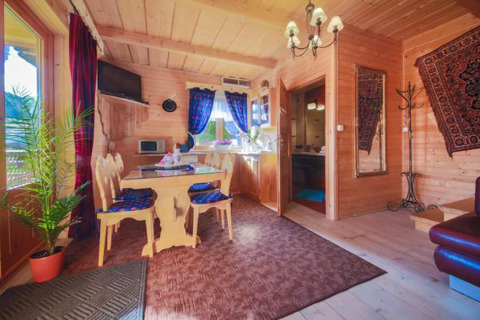 Knusse houten chalet met gezellige zithoek, eethoek, keuken en tapijten in de bergen van Tsjechië.