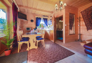 Knusse houten chalet met gezellige zithoek, eethoek, keuken en tapijten in de bergen van Tsjechië.