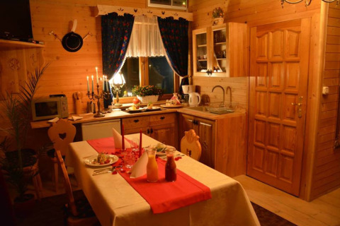 Knusse chaletkeuken met houten panelen, gedekte eettafel, kaarsen en landelijke sfeer in Tsjechië.