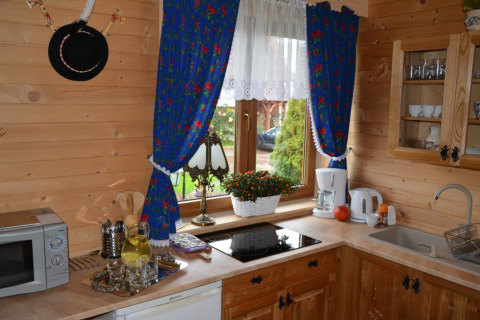 Knusse houten keuken met blauwe gordijnen, fornuis, microgolfoven en raam, chalet in Tsjechië.