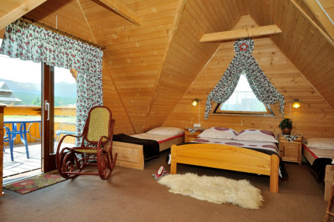 Knusse chaletkamer in de Tsjechische bergen met houten afwerking, bedden en uitzicht op de natuur.