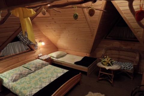 Gezellige slaapkamer met houten wanden en twee bedden in een chalet in Tsjechië, ‘s avonds verlicht.
