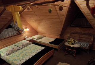 Gezellige slaapkamer met houten wanden en twee bedden in een chalet in Tsjechië, ‘s avonds verlicht.