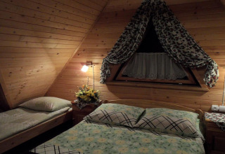 Slaapkamer in een gezellige berghut in Tsjechië met hout, dubbel bed en een driehoekig venster.