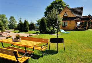 Tuin met gele zitbank, barbecue en chalet 'A fabulous house in the mountains' in Tsjechië bij zonlicht.