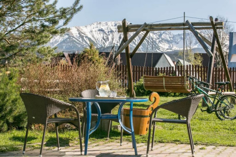 Buitenterras met zitjes, schommel en uitzicht op besneeuwde bergen bij chalet in de bergen in Tsjechië.