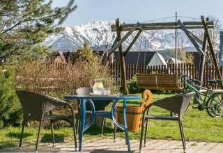 Buitenterras met zitjes, schommel en uitzicht op besneeuwde bergen bij chalet in de bergen in Tsjechië.