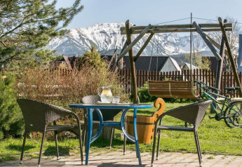 Patio esterno con tavolo, sedie, altalena e vista monti presso lo chalet “Una casa favolosa tra le montagne” in Cecchia.