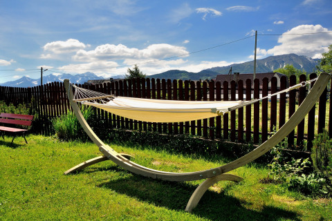 Een hangmat in een zonnige tuin met houten schutting en berguitzicht bij een chalet in Tsjechië.