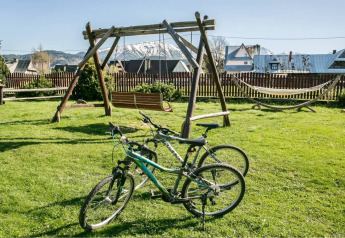Photo de deux vélos, d'une grande balançoire en bois et d'un hamac sur la pelouse du chalet «A fabulous house in the mountains» en République tchèque.