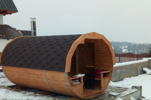 Houten tonvormige sauna bij een chalet in de sneeuw bij 'A fabulous house in the mountains', Tsjechië.