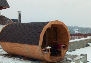 Houten tonvormige sauna naast een chalet in de sneeuw bij ‘A fabulous house in the mountains’, Tsjechië.