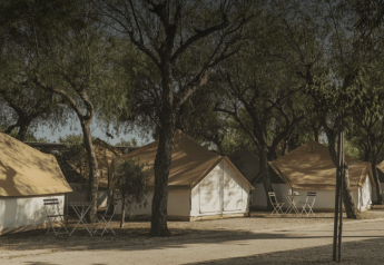 Safari-Zelte unter Bäumen mit Stühlen und Tischen davor, Bell Tent bei Wecamp Jávea in Spanien.