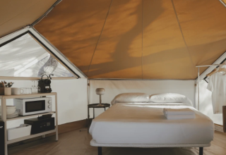 Innenansicht des Bell Tent im Wecamp Jávea, Spanien, mit gemütlichem Bett und Küchenzeile.