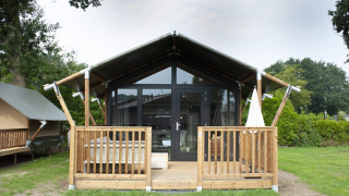 Tiny Safari House, een safaritent met houten terras, op Vakantiepark De Boshoek in Nederland in de zomer.