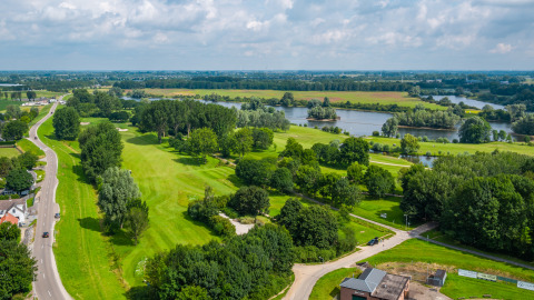 Landschapszicht op groene velden, rivier en bomen nabij een glamping accommodatie in het buitengebied.