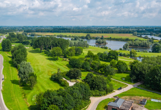 Landschapszicht op groene velden, rivier en bomen nabij een glamping accommodatie in het buitengebied.
