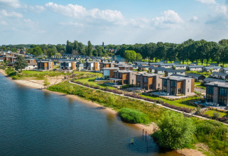 Vue aérienne de lodges glamping modernes en bord de lac, entourés de verdure et de nature paisible.