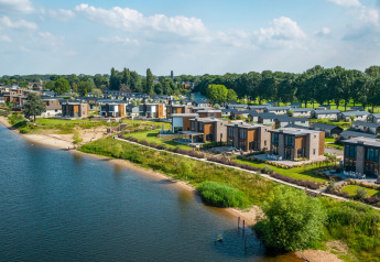 Vue aérienne de lodges glamping modernes en bord de lac, entourés de verdure et de nature paisible.