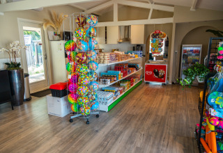 Negozio glamping con palloni colorati, snack, bevande e freezer per gelati, ambiente luminoso e moderno.