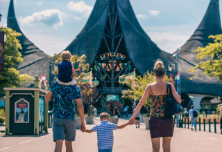 Famille marchant vers un bâtiment féerique par une journée ensoleillée dans un hébergement glamping.