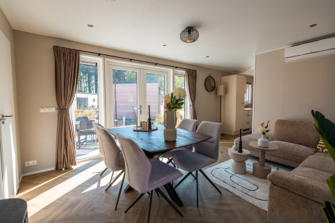 Modern living and dining area with sunlight at Groeneborg Lodge met Hottub, Vakantiepark De Wiltzangh, Netherlands.