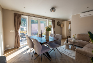 Modern living and dining area with sunlight at Groeneborg Lodge met Hottub, Vakantiepark De Wiltzangh, Netherlands.