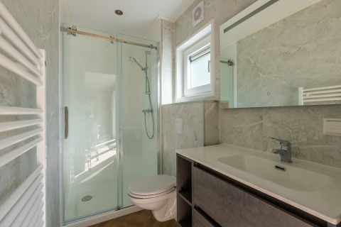 Modern badkamer met douche, toilet, wasbak en spiegel in Groeneborg lodge op De Wiltzangh park.