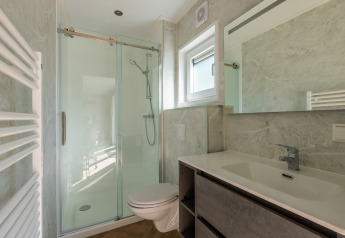 Moderne badeværelse med bruser, toilet, håndvask og stort spejl på Groeneborg lodge på De Wiltzangh.