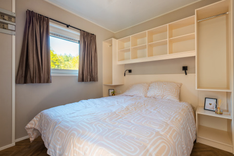 Bright and cozy bedroom with double bed, window, and open storage at Groeneborg Lodge in the Netherlands.