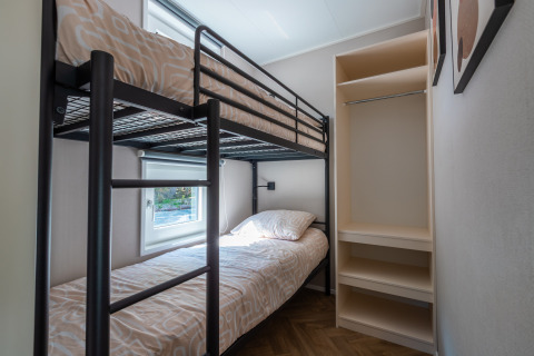 Dormitorio con literas y estantería en Groeneborg lodge con jacuzzi, Vakantiepark De Wiltzangh, Países Bajos.