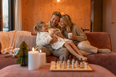 Familie hygger sammen på sofaen i Unbrick One Family på De Weelderik, Holland, omgivet af stearinlys.