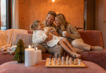 Gezin geniet samen op de bank bij Unbrick One Family, De Weelderik, Nederland, met kaarsen aan.
