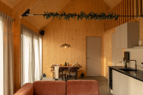 Modern houten lodge-interieur met eettafel en keuken in Unbrick One Family bij De Weelderik, Nederland.
