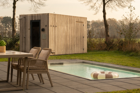 Lodge im Freien mit Esstisch, Stühlen, kleinem Pool mit Schwimmring und moderner Holzsauna.