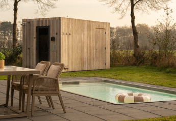 Lodge extérieur avec table à manger, chaises, petite piscine à bouée et sauna en bois moderne.