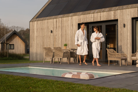 Par i badekåber nyder deres ophold ved sauna og pool ved Unbrick One lodge på De Weelderik, Holland.