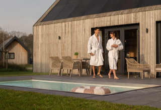Ein Paar in Bademänteln entspannt sich am Pool am Unbrick One | Sauna und Pool in De Weelderik, Niederlande.