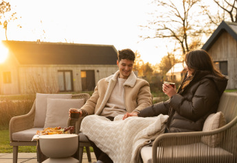 Couple relaxing outdoors at sunset at Unbrick One | Sauna and Pool at De Weelderik lodge in the Netherlands.