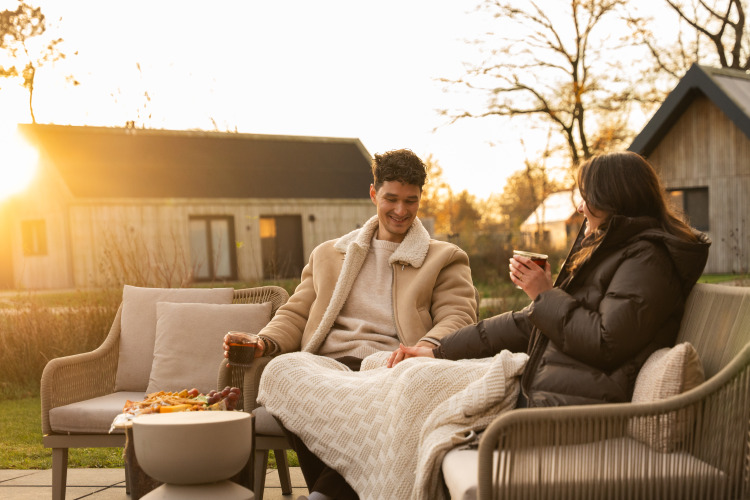 Pareja disfrutando al aire libre al atardecer en Unbrick One | Sauna and Pool en De Weelderik lodge, Países Bajos.