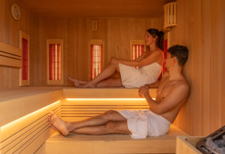 To personer slapper af i en moderne sauna med træpaneler på Unbrick One | Sauna and Pool lodge.