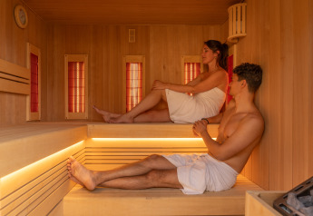 Zwei Personen entspannen in einer modernen Sauna mit Holzverkleidung im Unbrick One | Sauna and Pool.