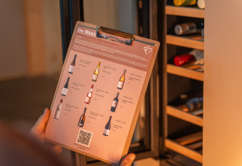 Une personne tient une carte des vins devant une cave à vin au Unbrick One Lodge avec sauna et piscine.