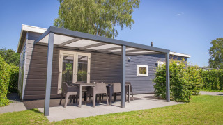 Veluwelodge XL en Holiday park De Boshoek, Países Bajos, con patio cubierto y mobiliario de jardín.